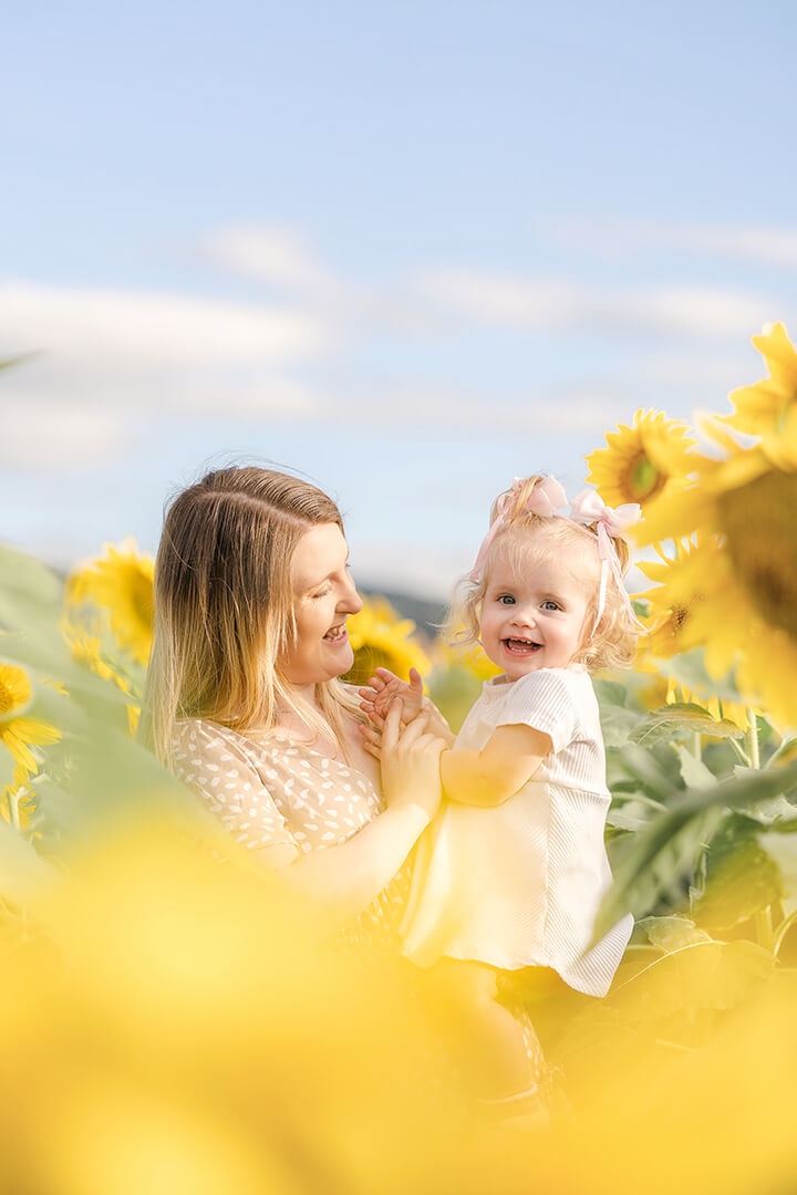 mum holding toddler in flower field having family photos taken in adelaide sunflower field.