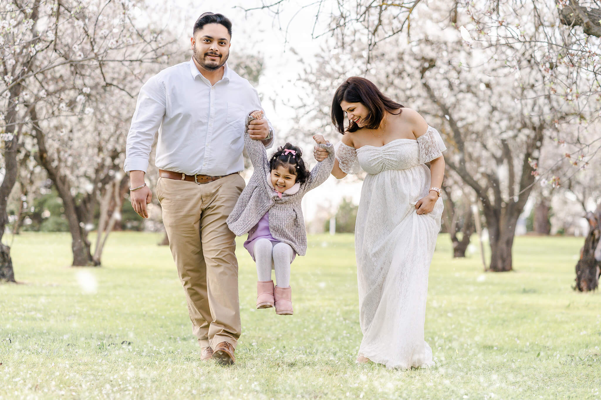 family of three having professional photoshoot in adelaide amongst almond blossoms season in o'halloran hill.